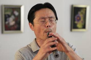 Musician Hong Wang plays a guan in his home Tuesday, July 3, 2012.